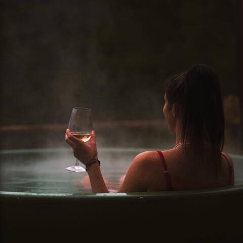 Woman holding a glass of wine in a hot tub
