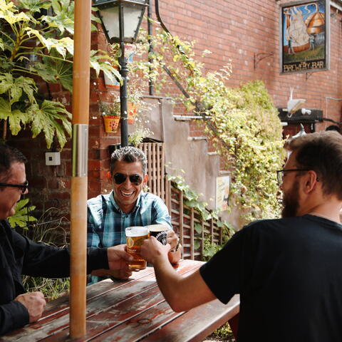 Men toast a pint at the barrels in hereford