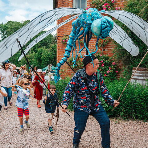 Man walking with large insect sculpture