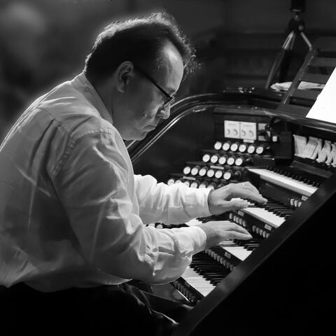 Monochrome image of a man playing a church organ