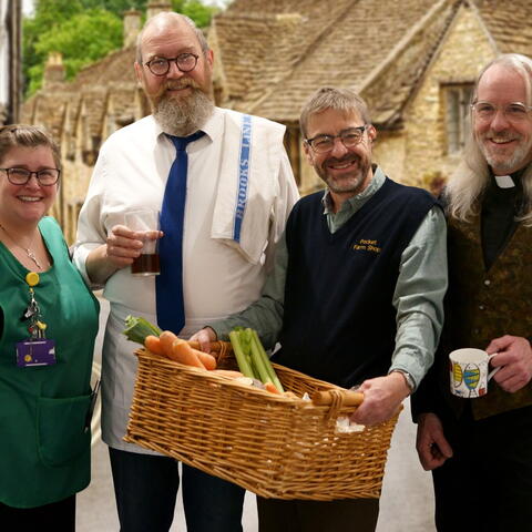 4 people holding basket of vegitables