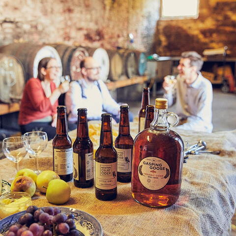 bottles of cider on a table with people sat in the background