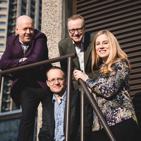 4 people leaning on railings of steps outside a building