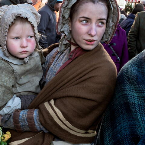 woman dressed in Victorian clothes holding a child