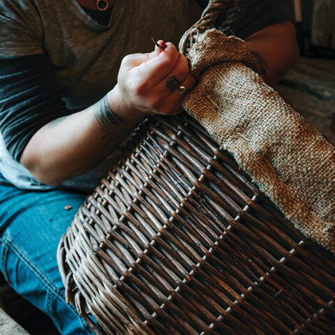 Person weaving a large willow basket