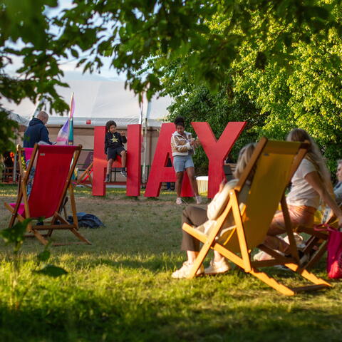 Hay Festival sign and people sat in the sunshine