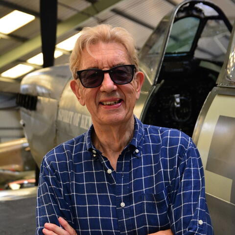A person wearing sunglasses and wearing a blue checked shirt
