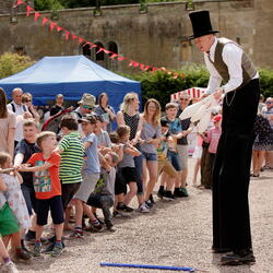 Juggler on stilts performing for a crowd at Eastnor Vintage